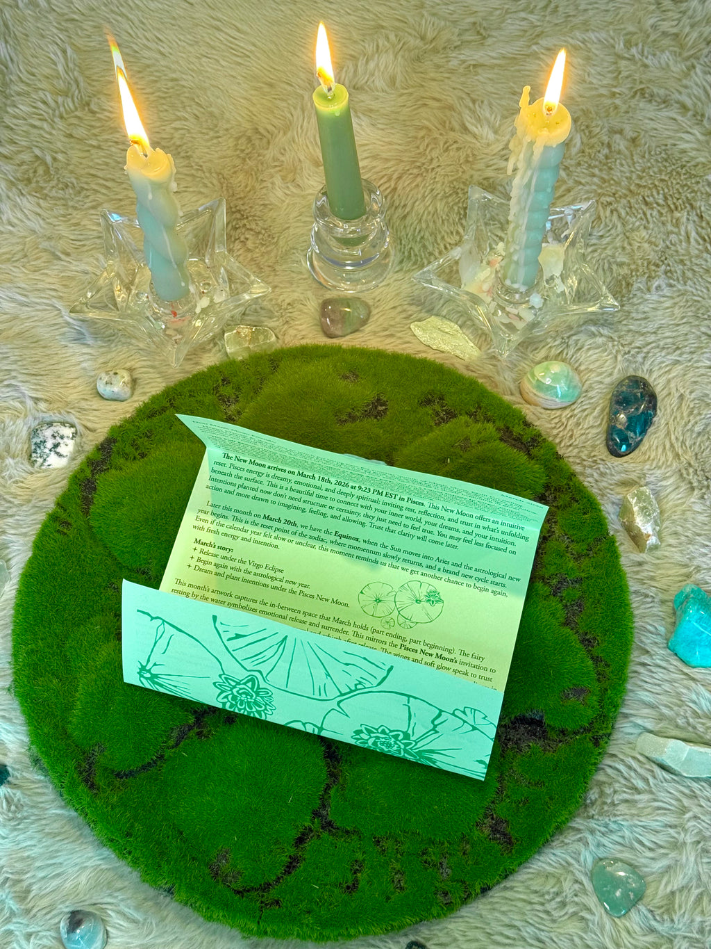 Candles around a green felt circle with a card on top, on a textured surface.