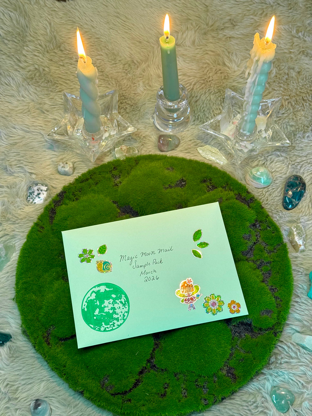 Green greeting card with floral designs on a mossy surface with lit candles.