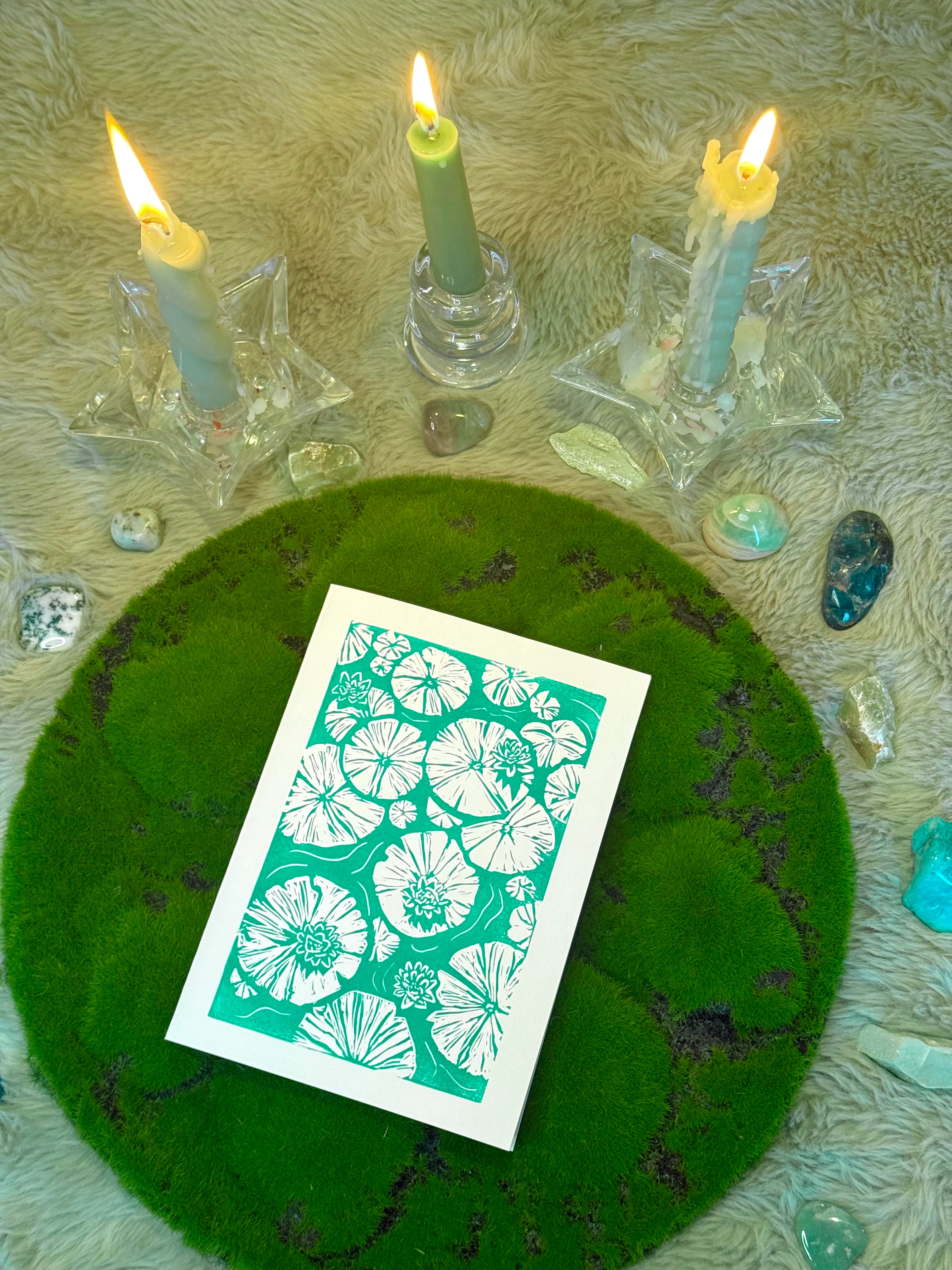 Card with floral design on a green stone surface with candles and crystals.