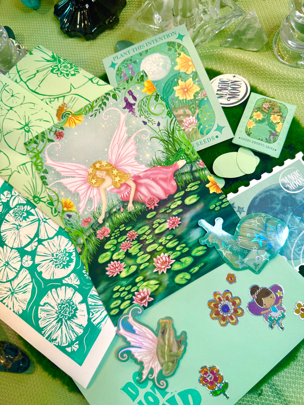 Collection of fairy-themed cards and stickers on a green surface