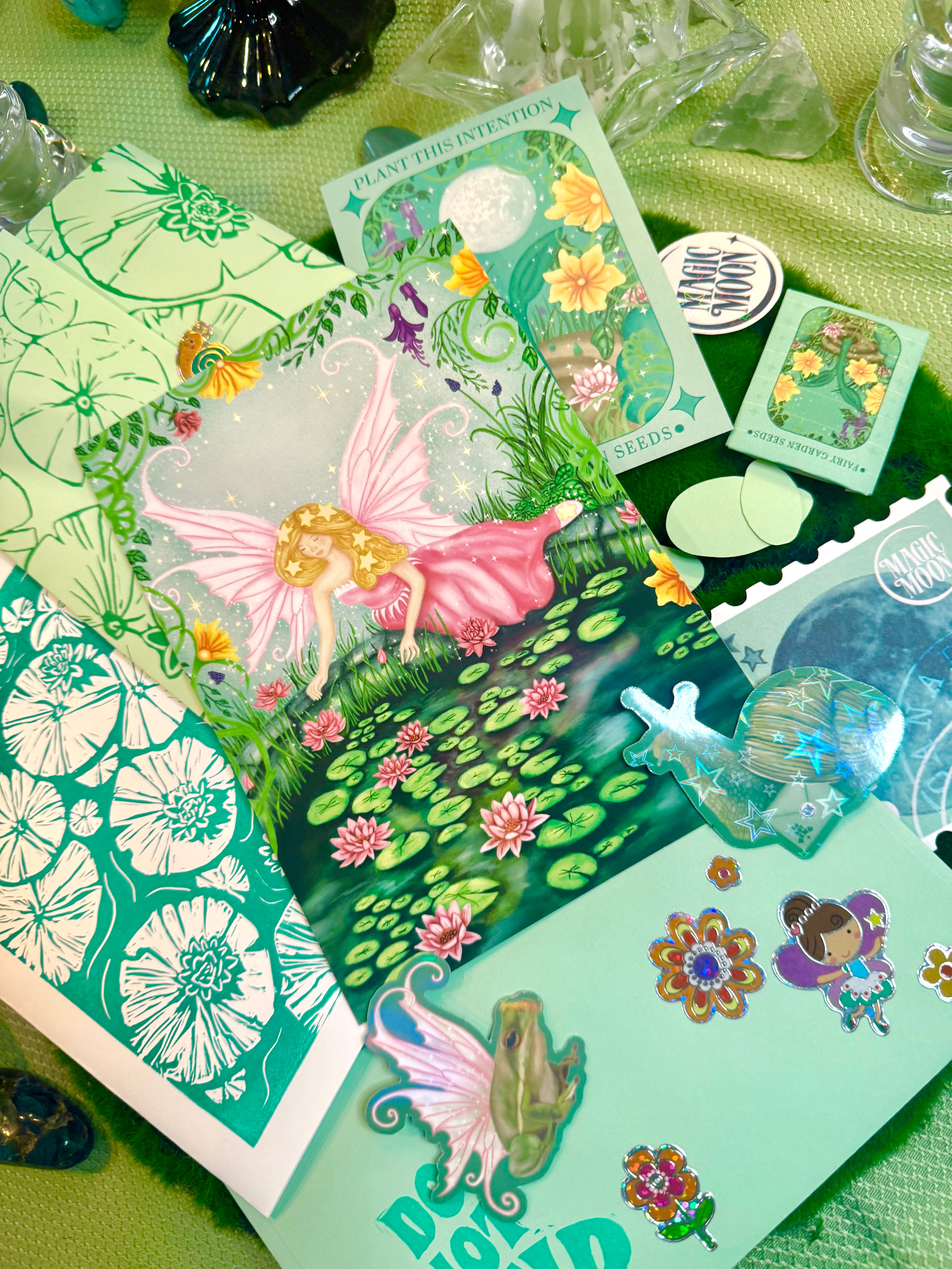 Collection of fairy-themed cards and stickers on a green surface
