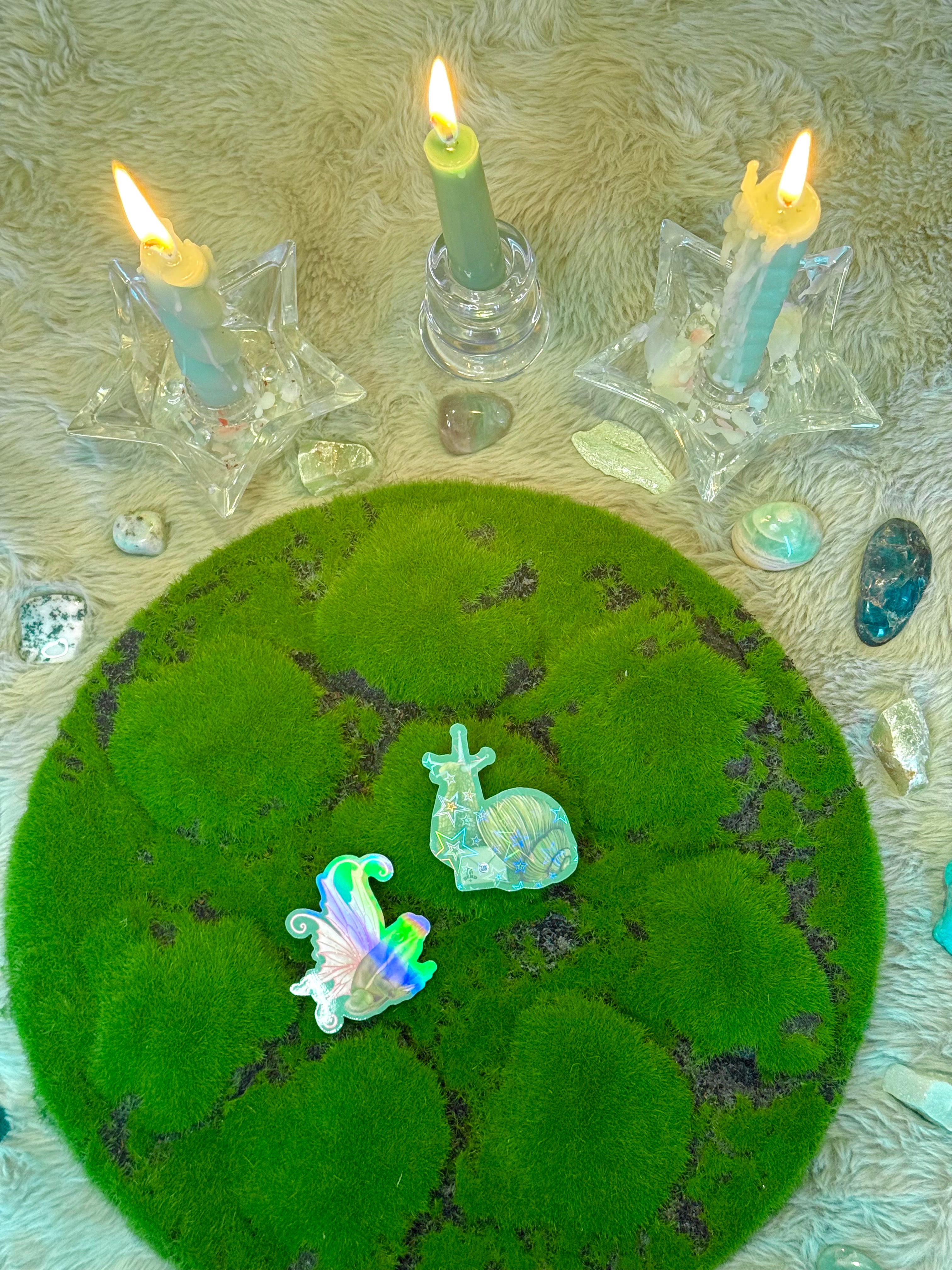 Mossy circle with fairy figurines and candles on a textured surface